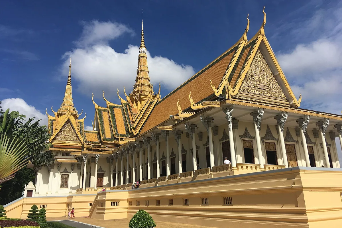 Pozlacené střechy a věže Trůnního sálu v Královském paláci v Phnom Penhu pod modrou oblohou.
